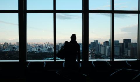 silhouette of a person standing in front of a window looking at the city